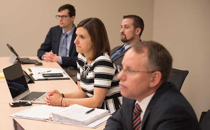 Photo of MBA students at a table listening to a lecture